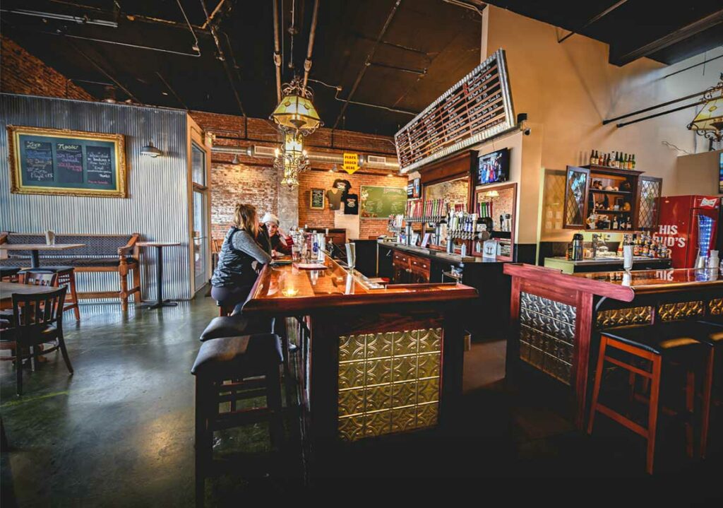 A renovated commercial space in Fort Collins, Colorado, featuring a local cidery. The exterior boasts a blend of rustic charm and modern design, with inviting signage and outdoor seating. Through large windows, glimpses of the cozy interior with wooden accents and stainless steel equipment can be seen, inviting visitors to enjoy a craft cider experience.